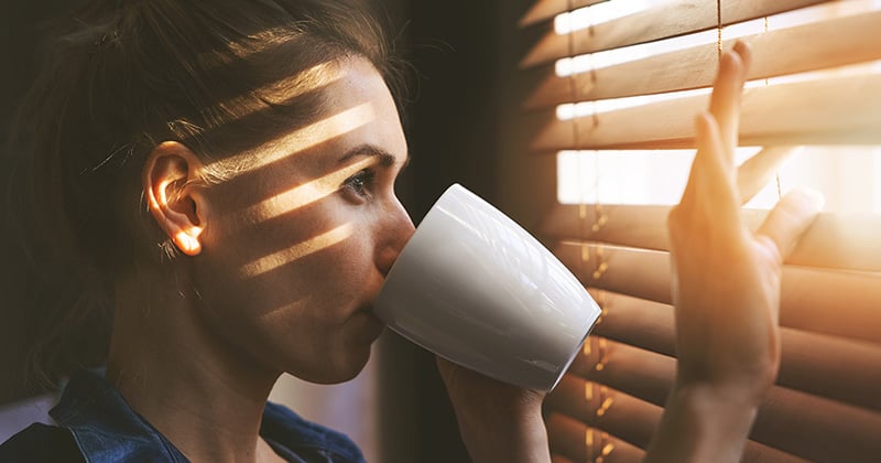 Image of woman looking through blinds